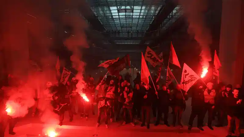 Demonstranci wdzierają się do paryskiej siedziby BlackRock, wymachując czerwonymi racami i rzucając bomby dymne. 
